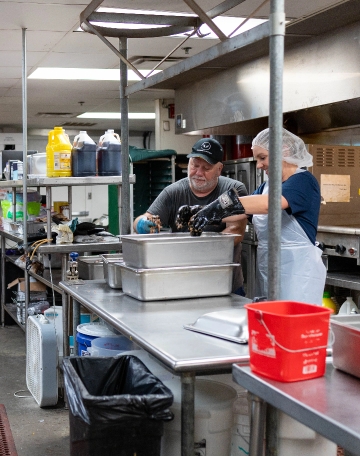 two kitchen workers prepping food