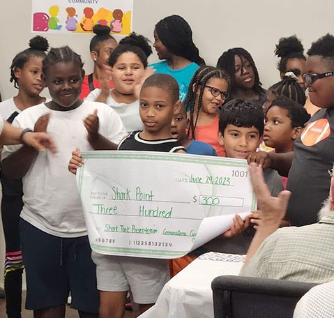 After School Enrichment Program students posing with a donation check